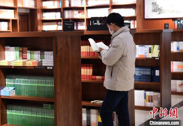 资料图：图为重庆书城恢复营业，市民戴着口罩翻阅图书。周毅 摄